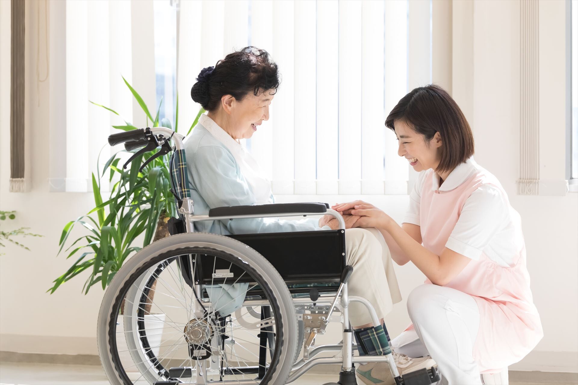 車いすの女性に寄り添う女性ヘルパー